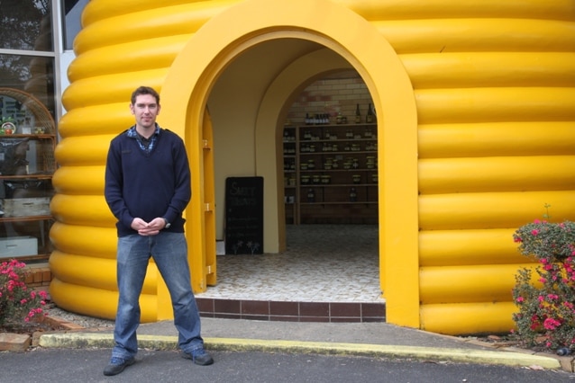 A man stands outside a yellow building