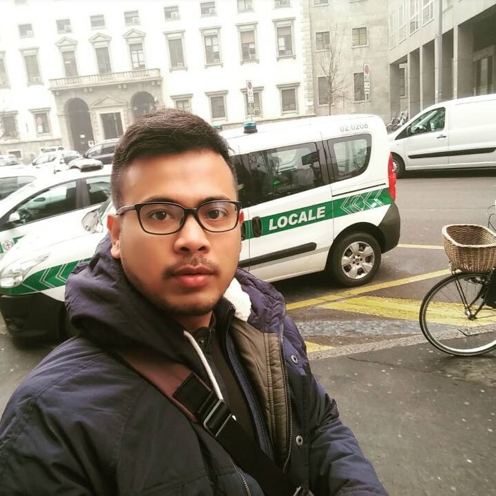 A portrait of Juno Simorangkir standing on the street, in front of a car.