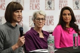 Rachel Crooks holds a microphone at a news conference with Jessica Leeds and Samantha Holvey next to her.