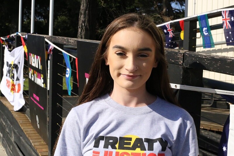 Shanoah smiles, wearing a "Treaty = Justice" t-shirt as she stands in front of the Frankston polling station.