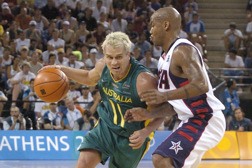 Basketball player dribbling with ball with an opposition player defending him during a game.
