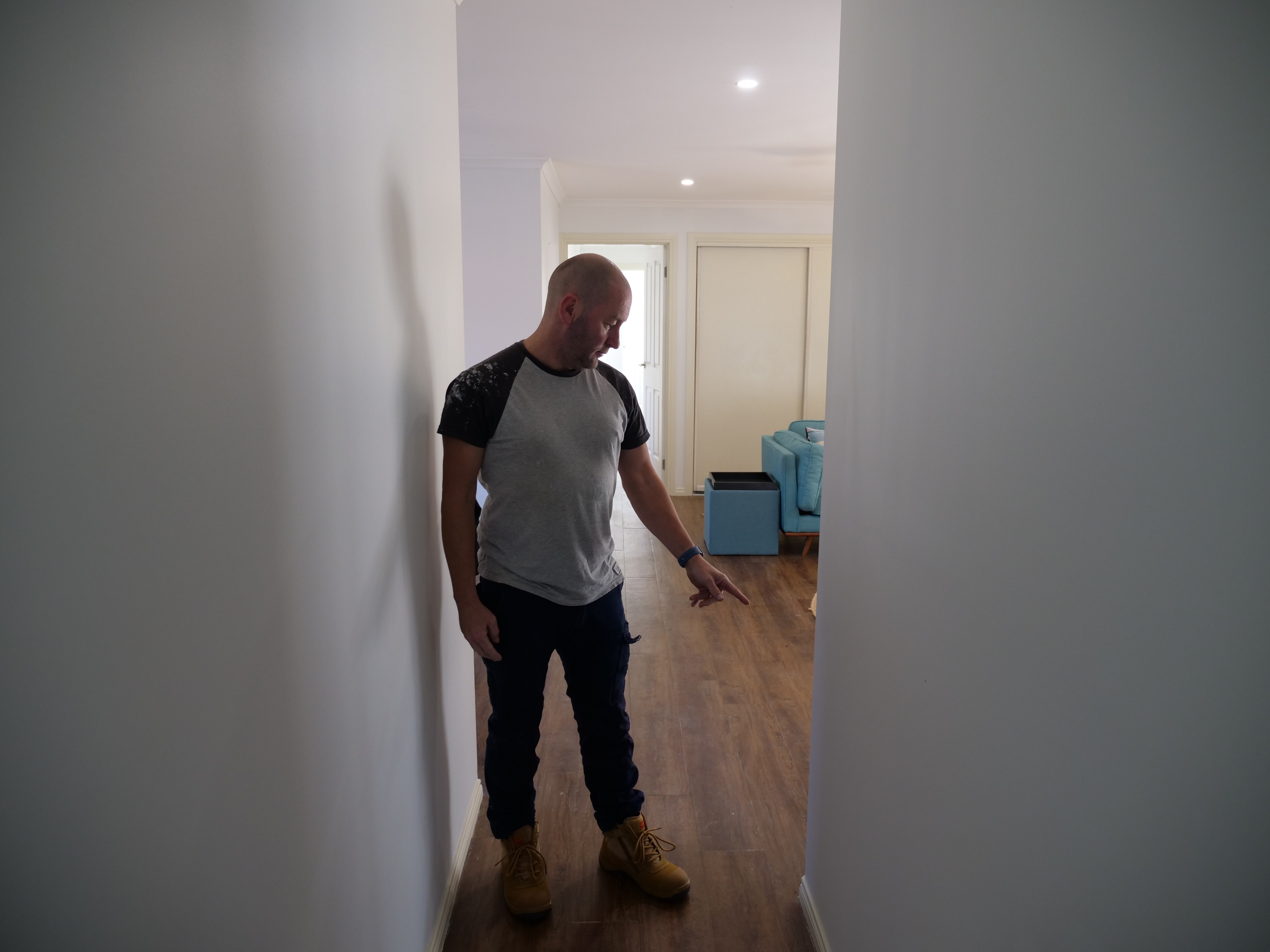 A man points to a wall.