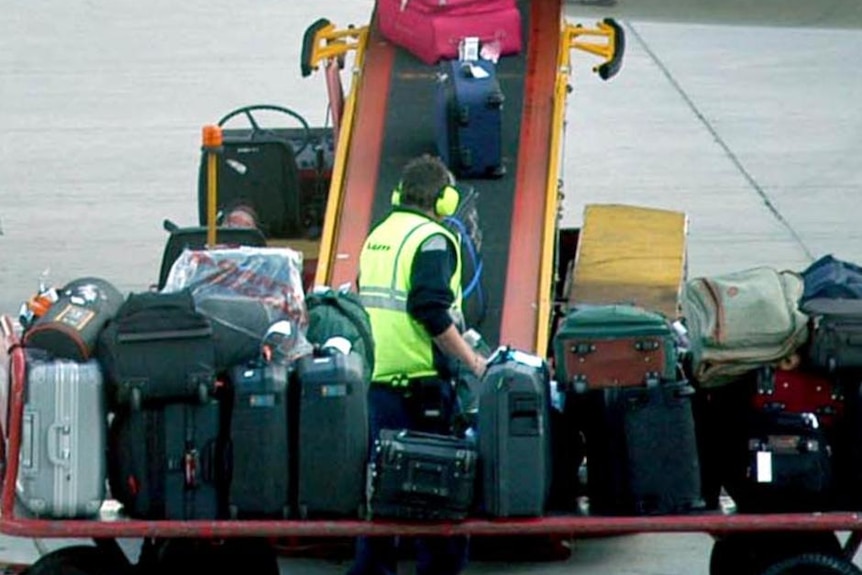 A baggage handler overlooks luggage being loaded on the plane.