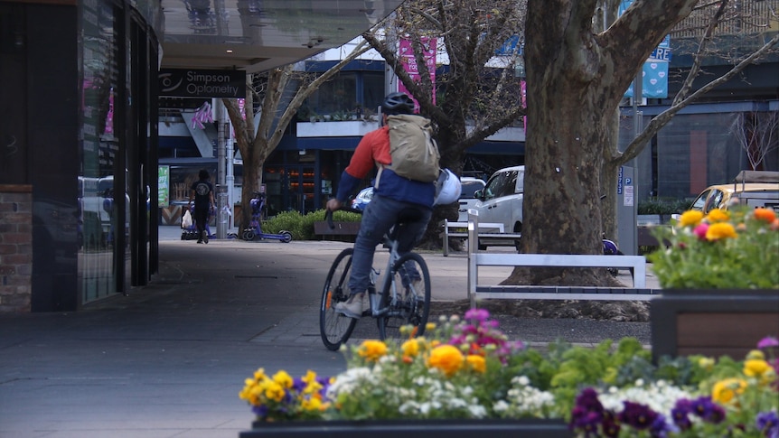 A person rides a bike through empty streets of a city centre.