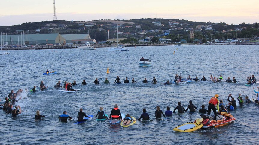 Dozens of surfers formed a circle in the ocean.