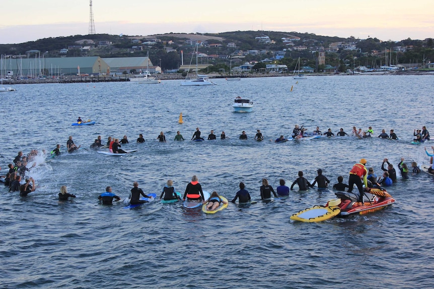 Dozens of surfers formed a circle in the ocean.