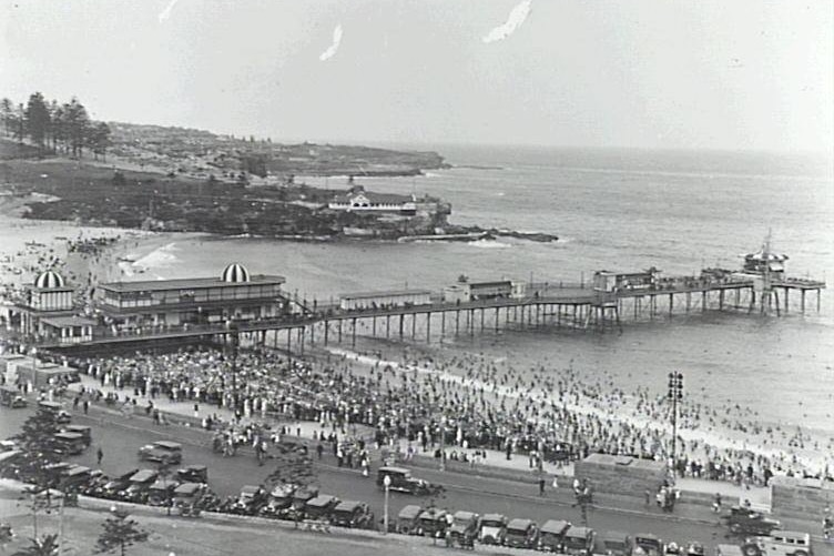 A black and white photograph of a pier and a beach