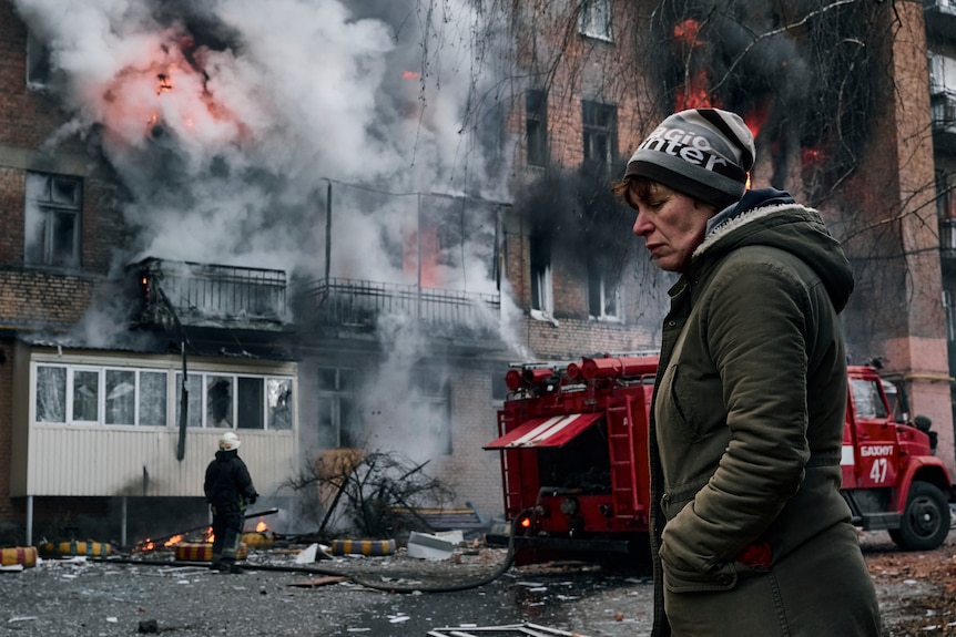 A local resident walks past her burning house after Russian shelling in Bakhmut.