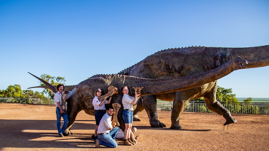 Dinosaur with people standing with skeleton pieces