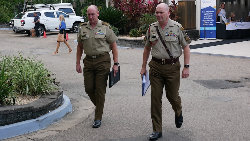 Two high-ranking soldiers walking along a driveway in a carpark