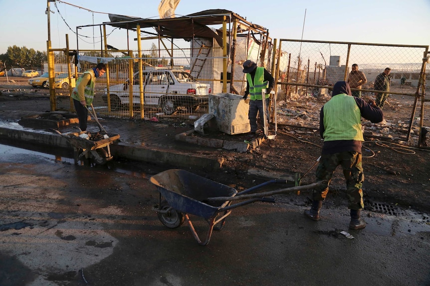 Workers clean up at the site of a car bomb in Baghdad.