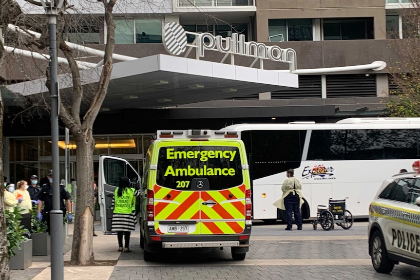 A medical officer is standing at the open door of an ambulance front of the Pullman Hotel in Adelaide.