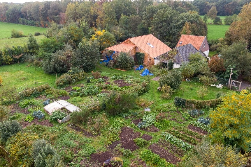 A bird's eye view of a house surrounded by several vegetable garden plots.