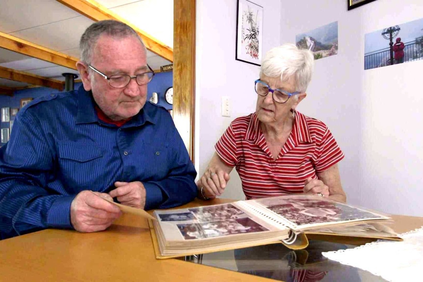 Dean and Leslie Howard sit at a table looking at pages of a photo album