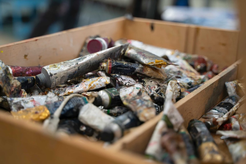 A close up of a box of paints, some without caps