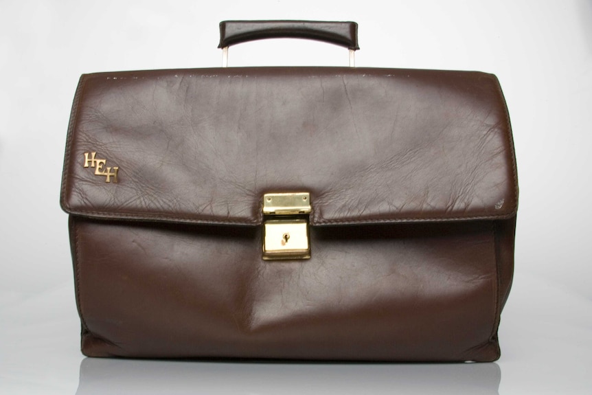 A photo of a brown leather briefcase with a gold monogram of the letter H, E, H.