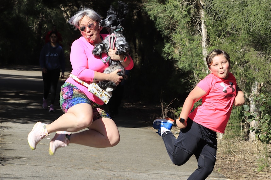 A woman holds her dog up for a jump shot.