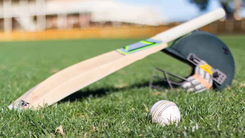 Cricket equipment sits on grass.