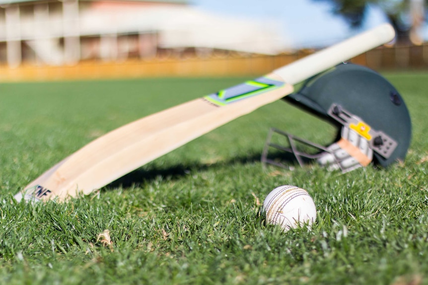 Cricket equipment sits on grass.