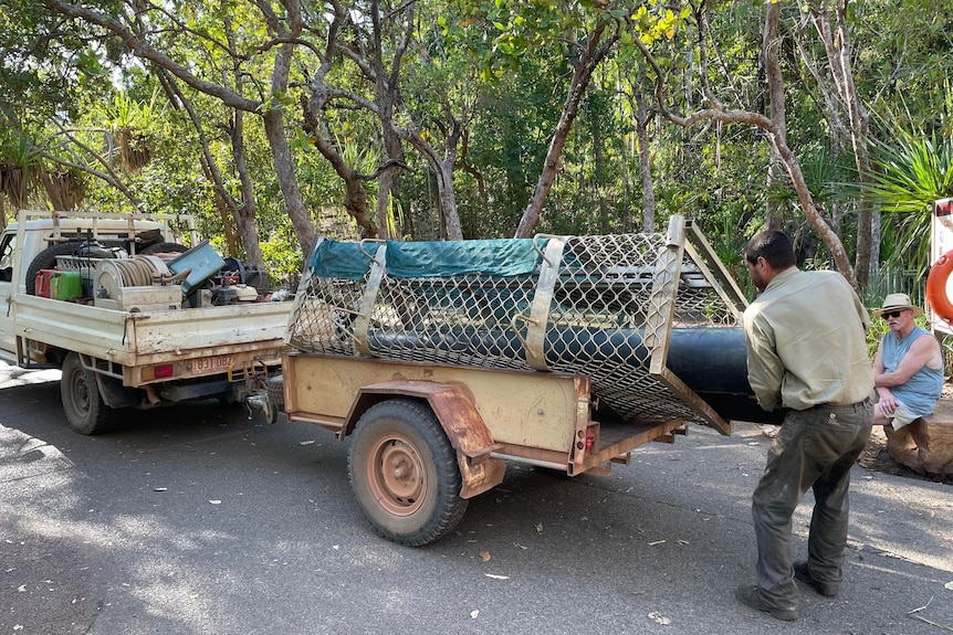 A park ranger taking a mesh-fence crocodile trap out of a wagon