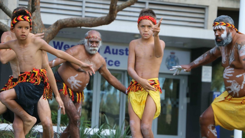 Aboriginal boys and men dance in traditional dress in front of police headquarters in Perth