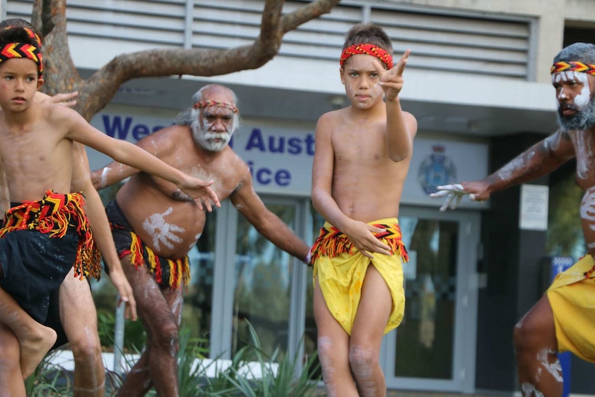 Aboriginal boys and men dance in traditional dress in front of police headquarters in Perth