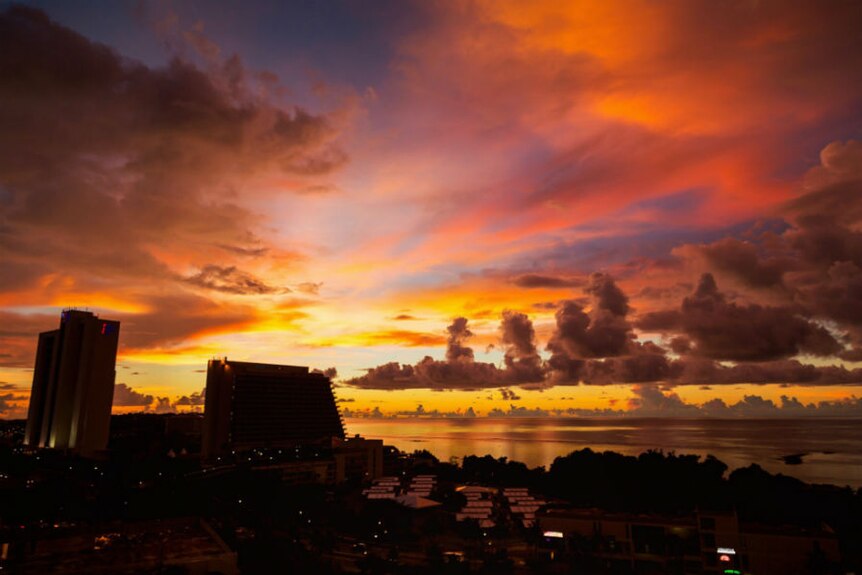 Stunning red and orange sunset over beach and skyline in Guam.