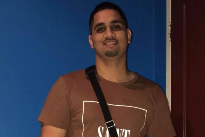 Fazan Khan wears a brown shirt and stands by a blue wall.