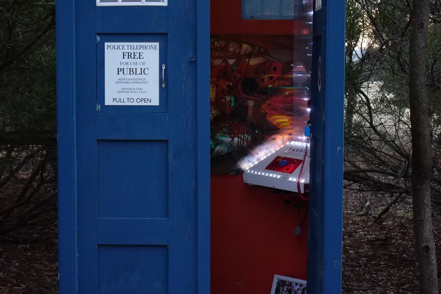The TARDIS phone box with its door open, showing bright lights and a table with buttons.