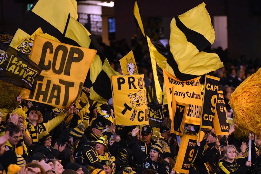 Tigers fans wave yellow and black banners and flags at the MCG.