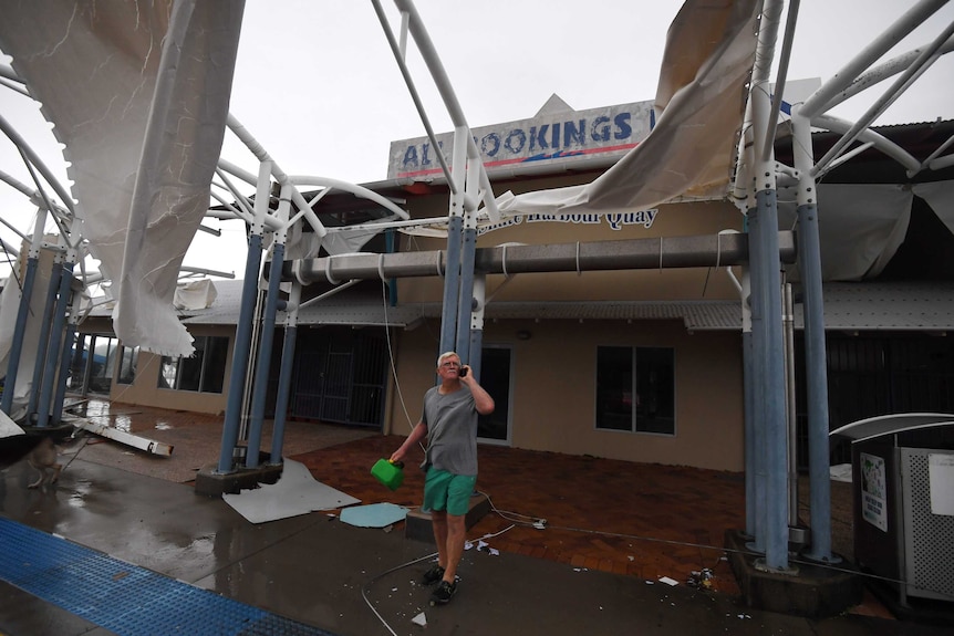 A local inspects damage to a boat terminal at Shute Harbour.
