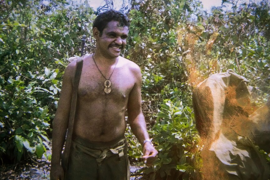 A topless soldier in Vietnamese jungle.