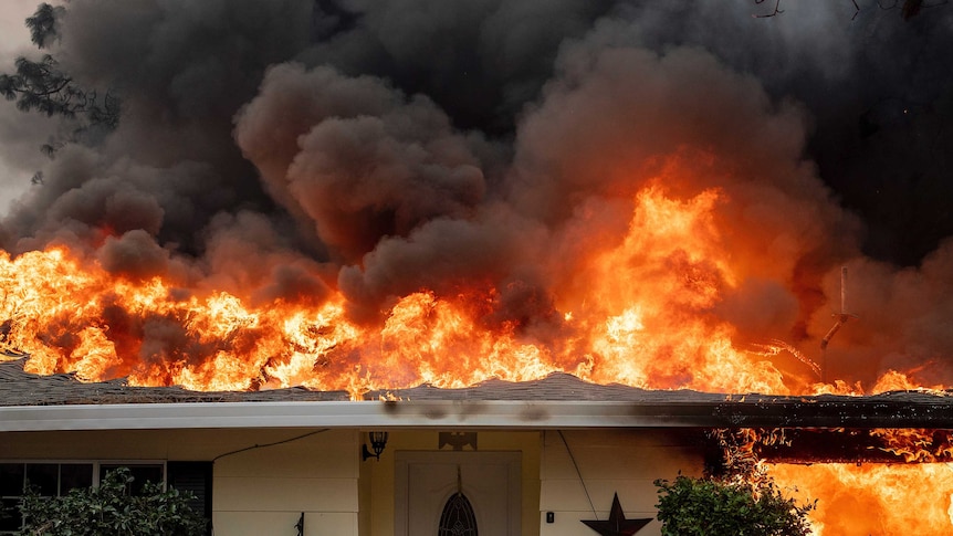 A home iis engulfed with flames as wildfires spread through Paradise, California