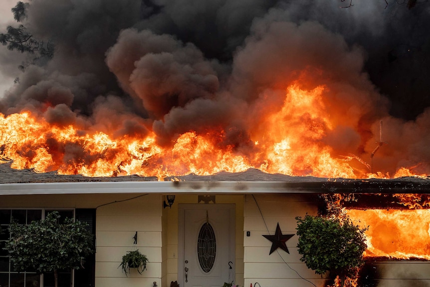 A home is engulfed with flames as wildfires spread through Paradise, California
