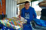 A man in a blue hoodie smiling in front of birthday presents.