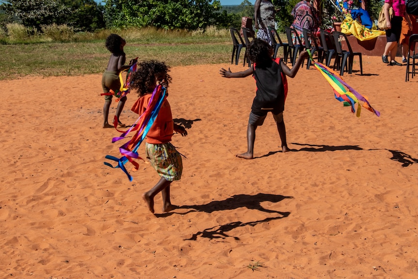 Kids play with ribbons on red sand