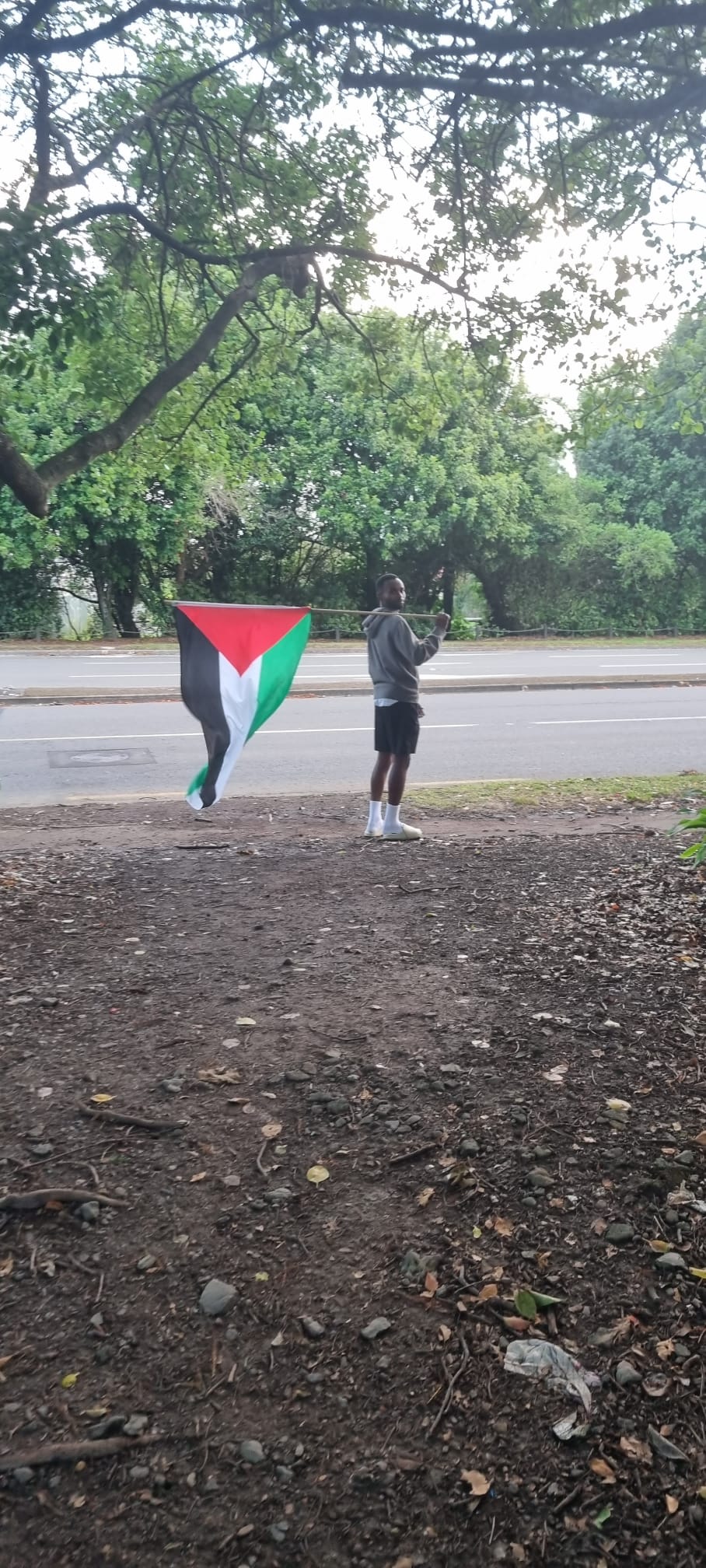 Suveen is pictured holding a pole with a palestinian flag over his shoulder.