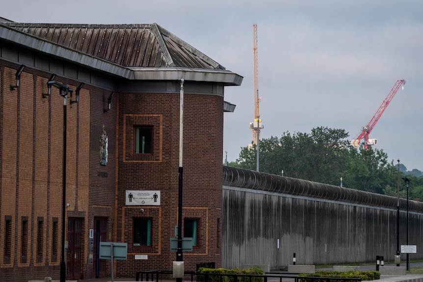 The outside of Belmarsh Prison, which has a brick facade and a towering concrete fence