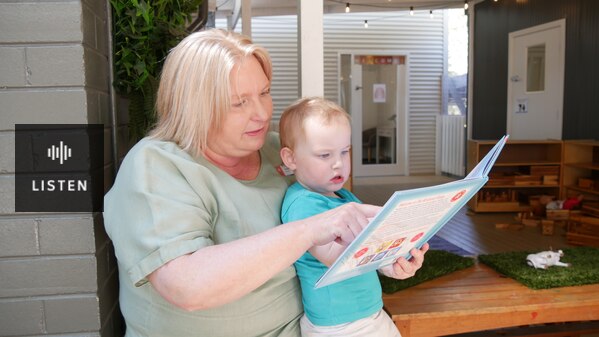 A woman wearing a green shirt is reading a book to a young boy. Has Audio.