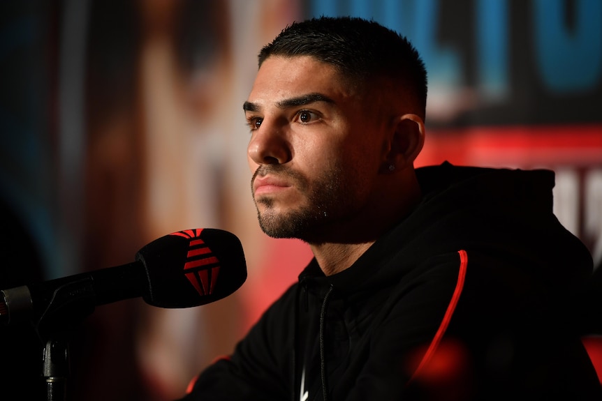 Boxer with a microphone stares to the left.