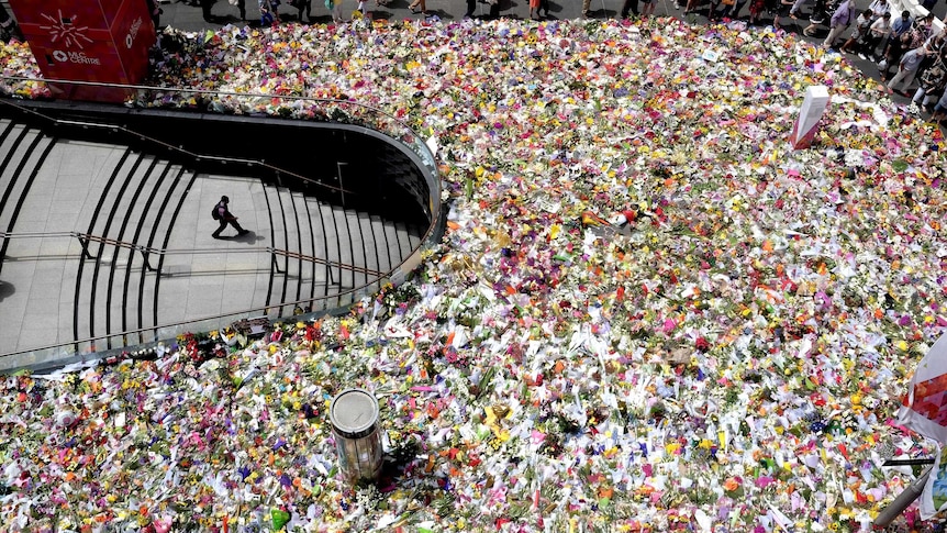 Hundreds of bunches of flowers surround a set of stairs leading underground