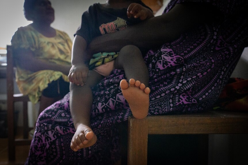 A photo of a toddler's feet sitting on a woman's lap.