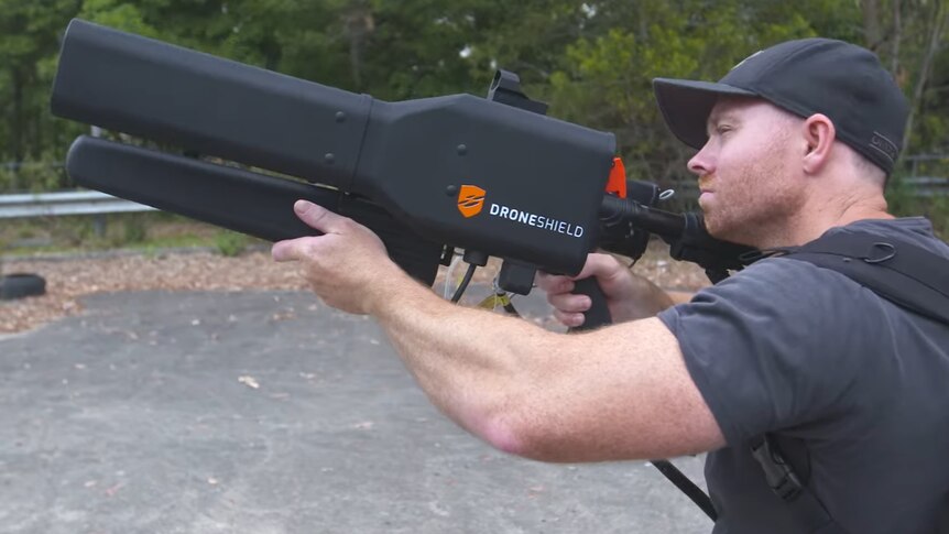 A man uses the DroneShield 'DroneGun' to take down a distant drone.
