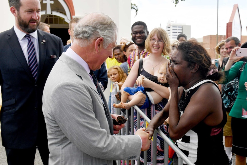 Prince Charles shakes hands with Elizabeth Kulla Kulla, who is clasping her hand over her mouth as she cries.