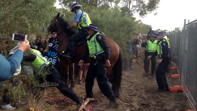 Police on horseback clash with protesters in bushland