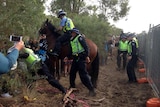 Police on horseback clash with protesters in bushland