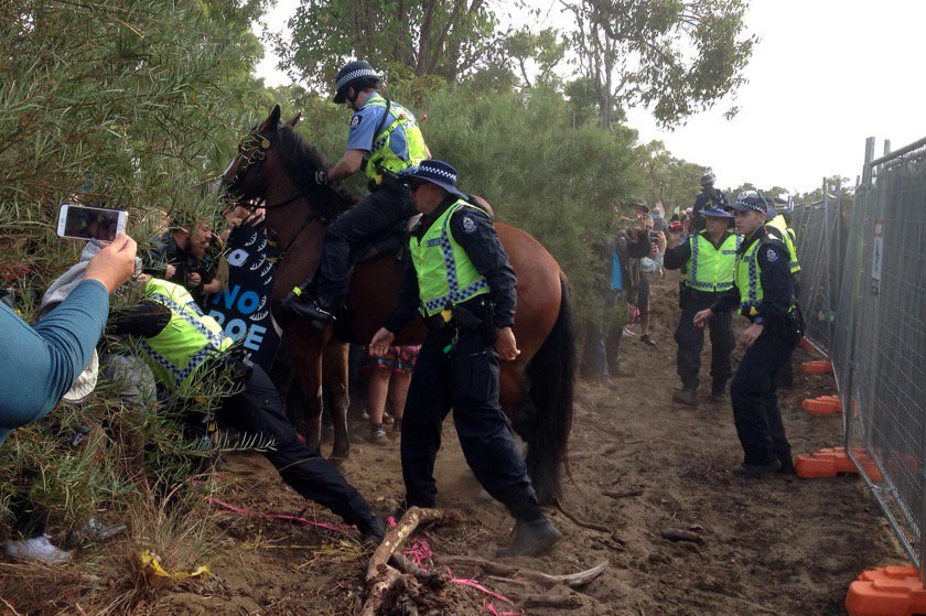 Police on horseback clash with protesters in bushland