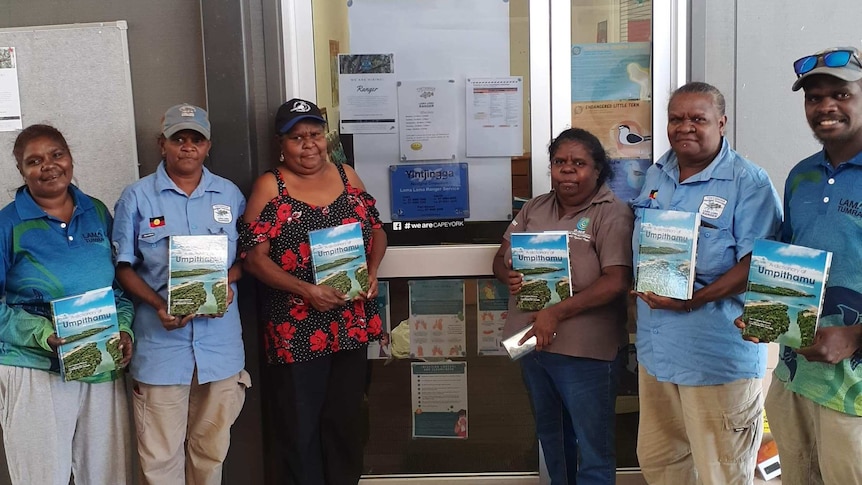 A group of Cape York Indigenous traditional owners display copies of a newly published dictionary of their traditional language.