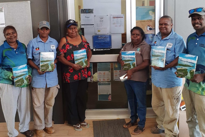 A group of Cape York Indigenous traditional owners display copies of a newly published dictionary of their traditional language.