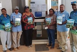 A group of Cape York Indigenous traditional owners display copies of a newly published dictionary of their traditional language.
